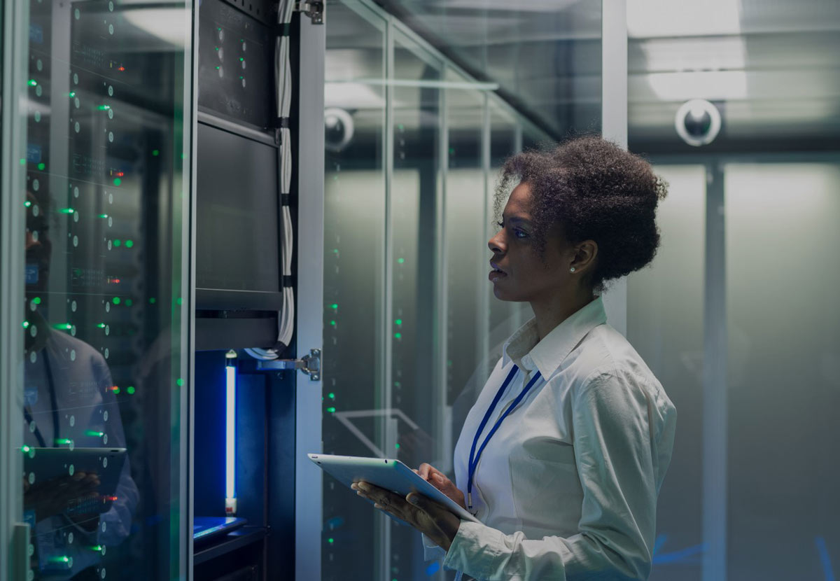 Femme avec une tablette à la main devant des serveurs informatiques